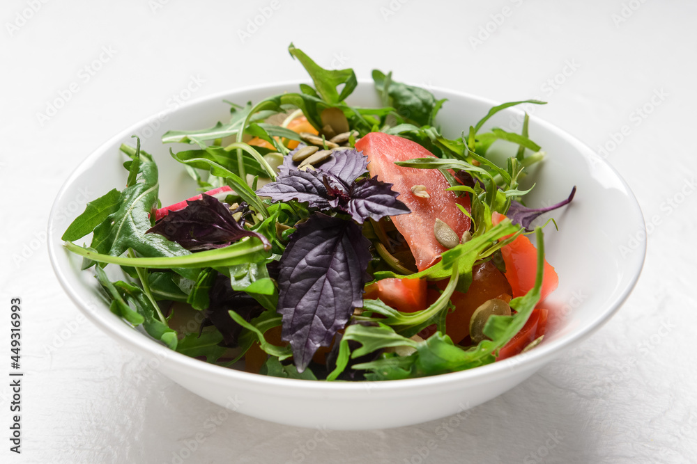 Bowl with tasty fresh salad on light background