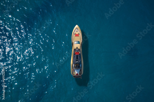 Super yacht on blue water top view. A huge super Mega yacht of gold color on blue water in Italy. Golden yacht open sea aerial view. © Berg