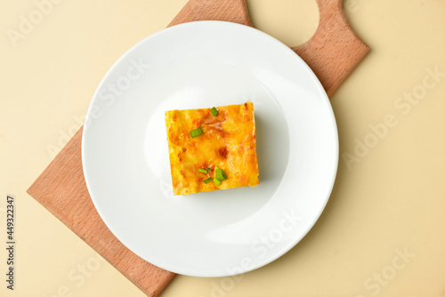 Plate with piece of mashed potato casserole on color background