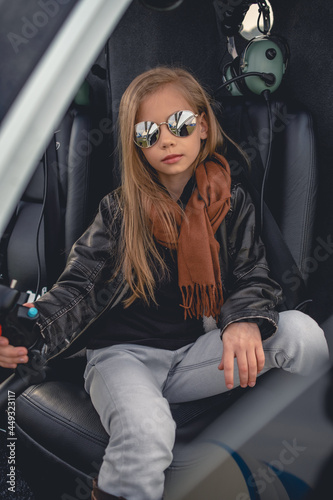 Fotografie Laid-back tween girl sitting on pilot seat in helicopter