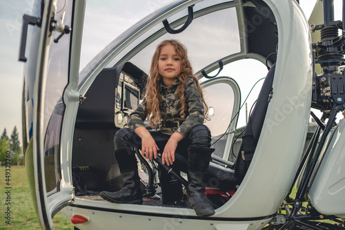 Confident preteen girl in camo style blouse sitting in open helicopter