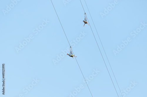 Two adventurers fly down a zip line rope in an extreme rope park