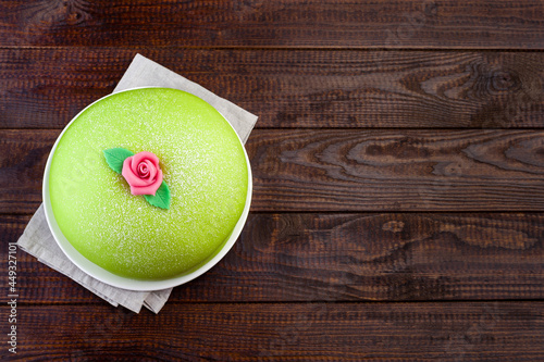 Princess cake with green marzipan cover and pink rose decoration, on dark wooden background, horizontal, top view, copy space photo