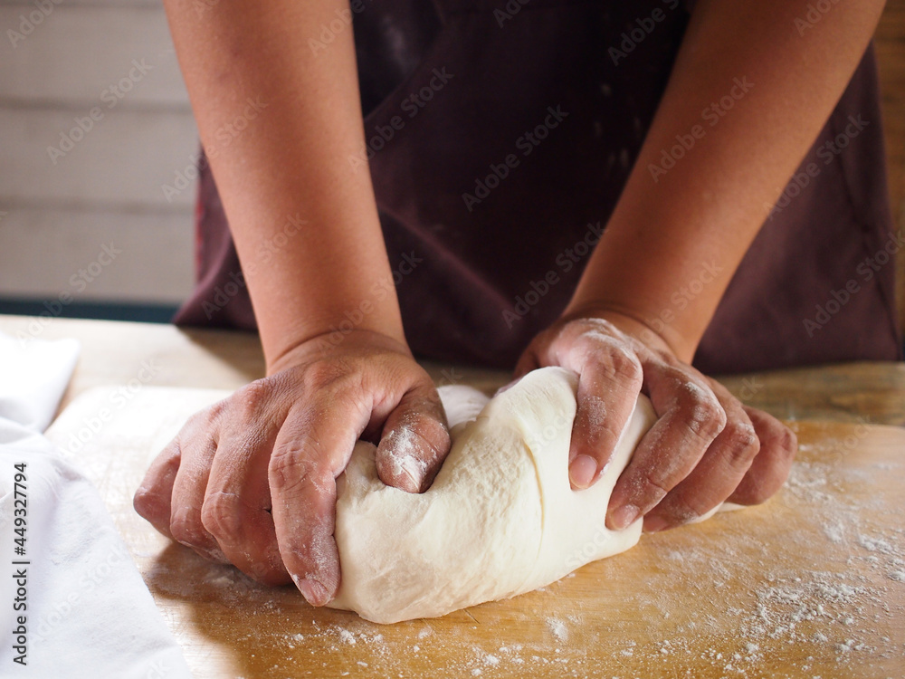 Woman hands making dough for pizza or bread in kitchen.