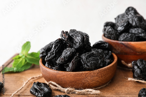 Bowl with tasty prunes on light background, closeup
