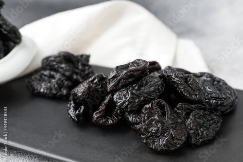 Board with tasty prunes on grey background, closeup