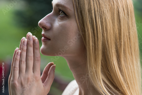 Portrait of a spiritual, young and attractive blonde girl. Lady pray to God with hope and faith