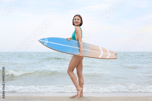 Canvas Print Beautiful young woman with surfboard on beach at resort