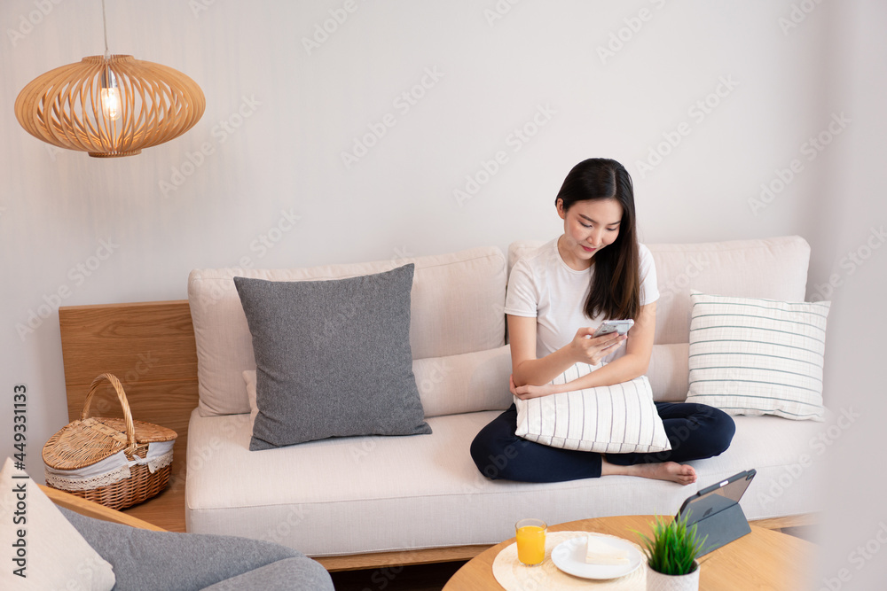 Living room concept a pretty girl sitting on the comfortable sofa spending her leisure on online with juice and snacks in the living room