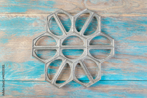 Old aluminum dumplings mold on blue wooden background.