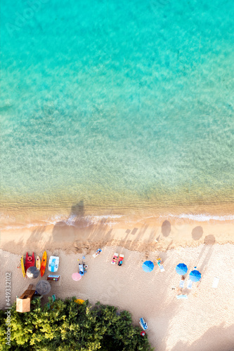 Obraz na płótnie View from above, stunning aerial view of a white sand beach bathed by a turquoise water and relaxed people under some beach umbrellas at sunset. Cala di volpe beach,Sardinia, Italy. w salonie