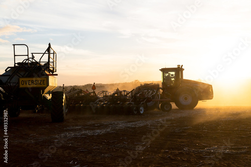 Tractor and air seeder planting wheat at sunset photo