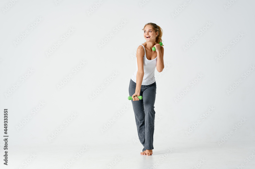 sportive woman with dumbbells in hands workout fitness exercise lifestyle light background
