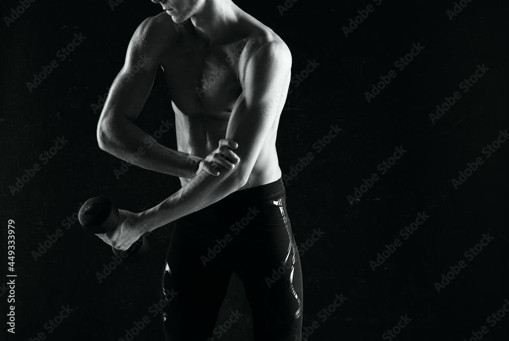 sporty man with dumbbells in hands pumping up muscles exercises dark background