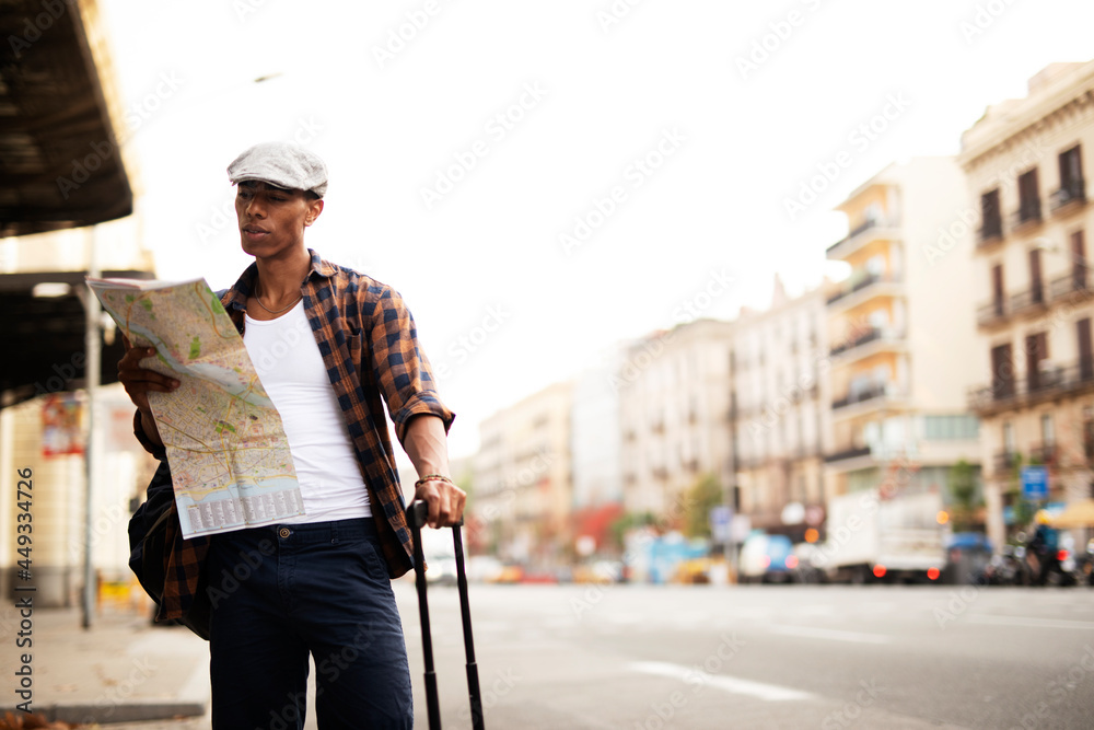 Happy young man with a city map. Young handsome male traveler, standing on the street and looking at the map.. Happy young man with a city map. Young handsome male traveler, standing on the street and looking at the map..