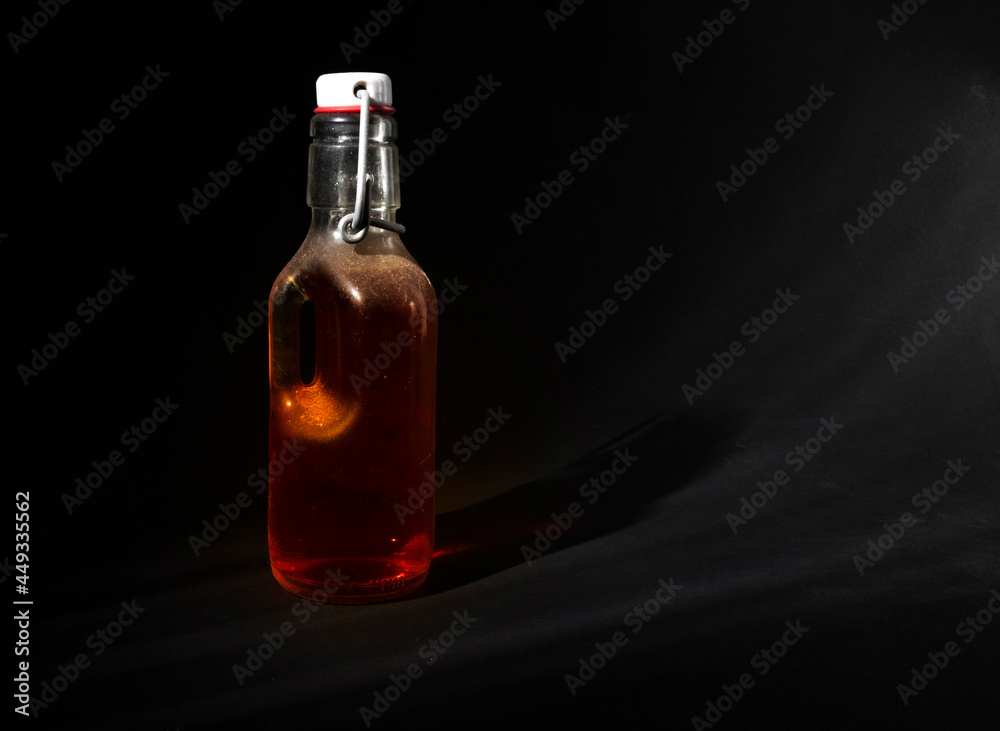 Glass bottle closed with a metal cap with an amber liquid inside Glass bottle closed with a metal cap with an amber liquid inside
