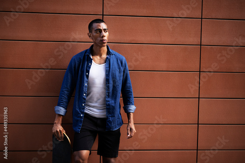 Portrait of happy african-american man with skateboard. Young handsome man with skateboard outdoors...