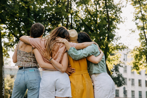 Group of four women friends, in a park, hugging together.