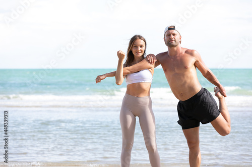 young athletic couple stretching and exercise together on the beach