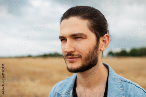 Portrait of young handsome guy in denim jacket on background of rainy clouds.