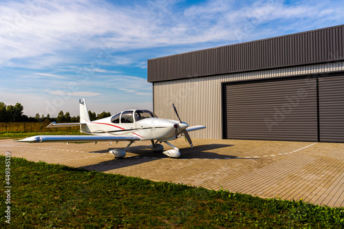 A small private white plane before the flight near the hangar.