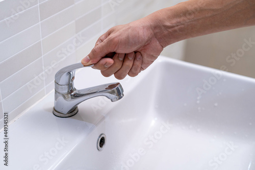 The faucet in the bathroom with running water. Man keeps turning off the water to save water energy and protect the environment. save water concept