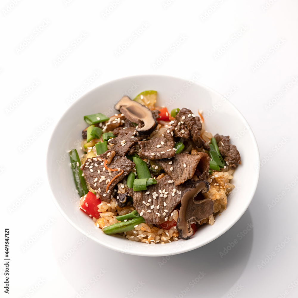 Stewed rice with dark meat, herbs, mushrooms and sesame seeds isolated on white background. Bowl of asian food. Pan-Asian cuisine. Soft focus. Stewed rice with dark meat, herbs, mushrooms and sesame seeds isolated on white background. Bowl of asian food. Pan-Asian cuisine. Soft focus.