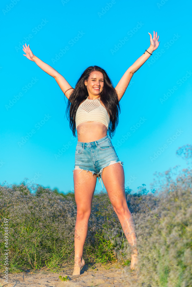 Joyful young girl raised his hands up and smiles. Happiness in lifestyle.woman raising her hands up in the blue air. Joyful young girl raised his hands up and smiles. Happiness in lifestyle.woman raising her hands up in the blue air.