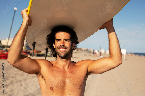 Portrait of handsome surfer with his surfboard. Young man with a surfboard on the beach
