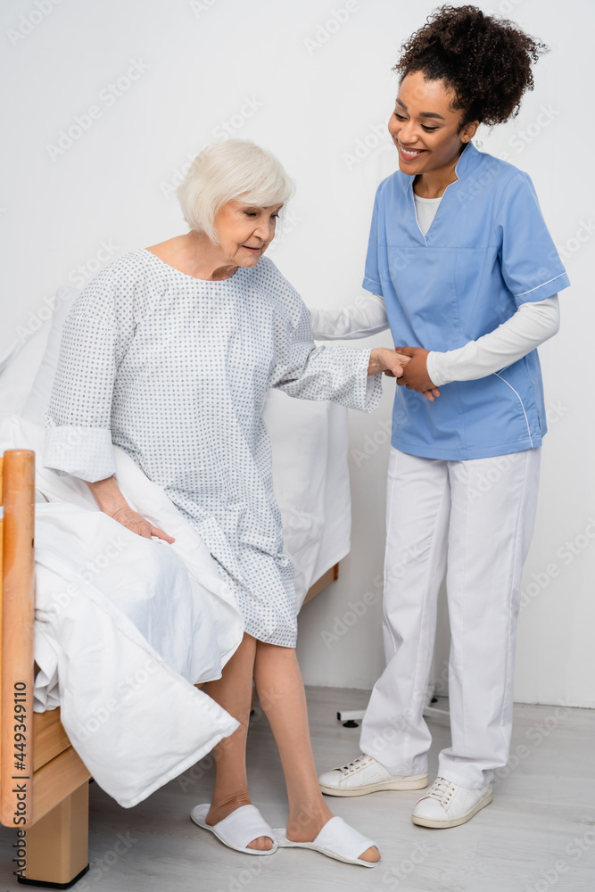 Smiling african american nurse holding hand of senior patient in hospital ward Smiling african american nurse holding hand of senior patient in hospital ward