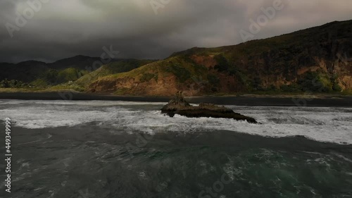 Drone fly to volcanic rock formation at Karekare black sand beach. Cloudy in New Zealand photo