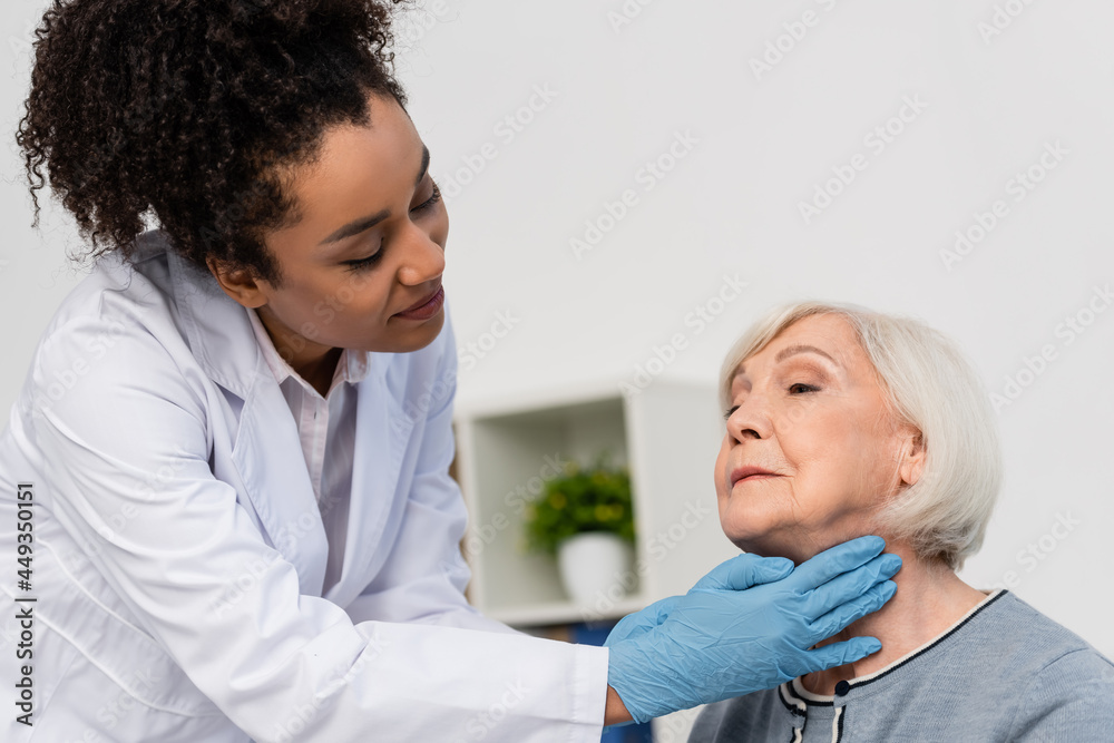 African american docktor in while coat checking neck of elderly patient African american docktor in while coat checking neck of elderly patient