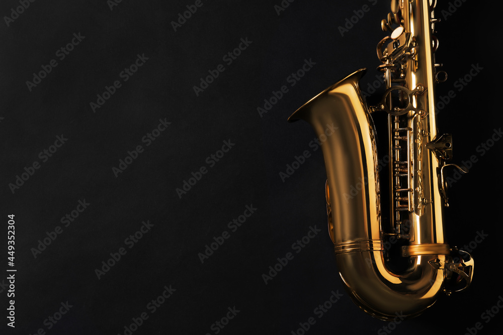 Obraz premium Beautiful saxophone on black background, top view. Space for text