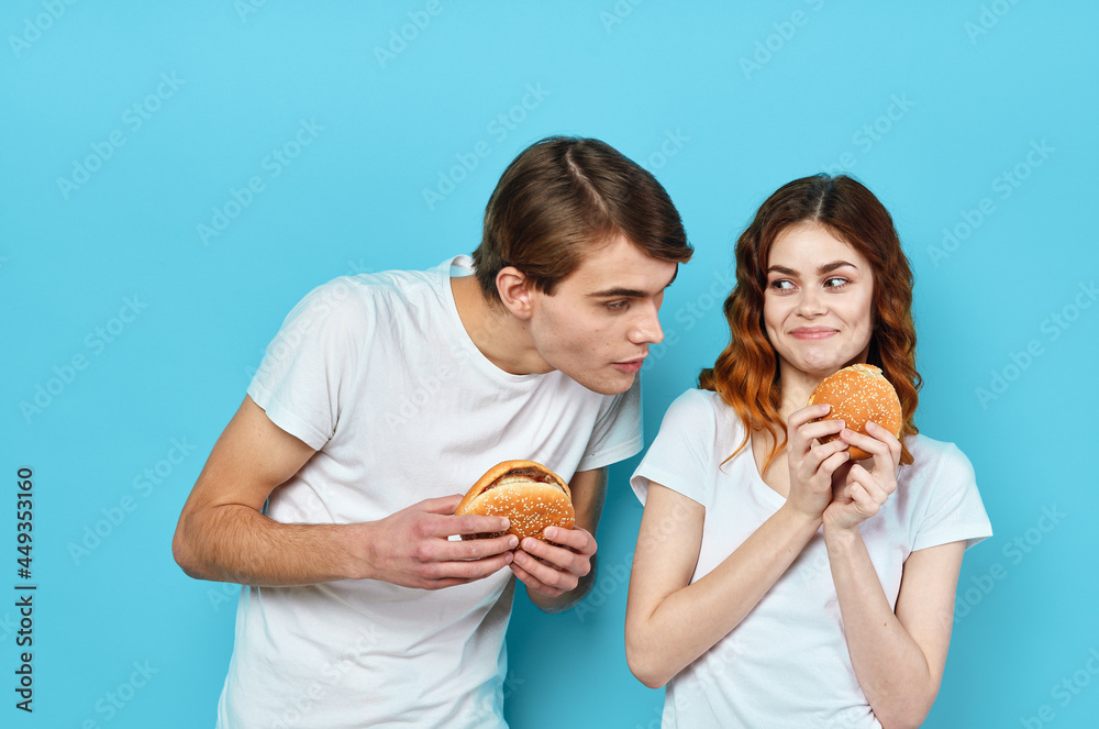 young couple hamburgers in hands snack lifestyle blue background young couple hamburgers in hands snack lifestyle blue background