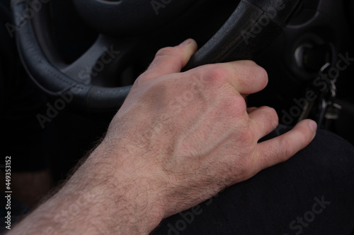 hand holds the steering wheel of a car  driving a car