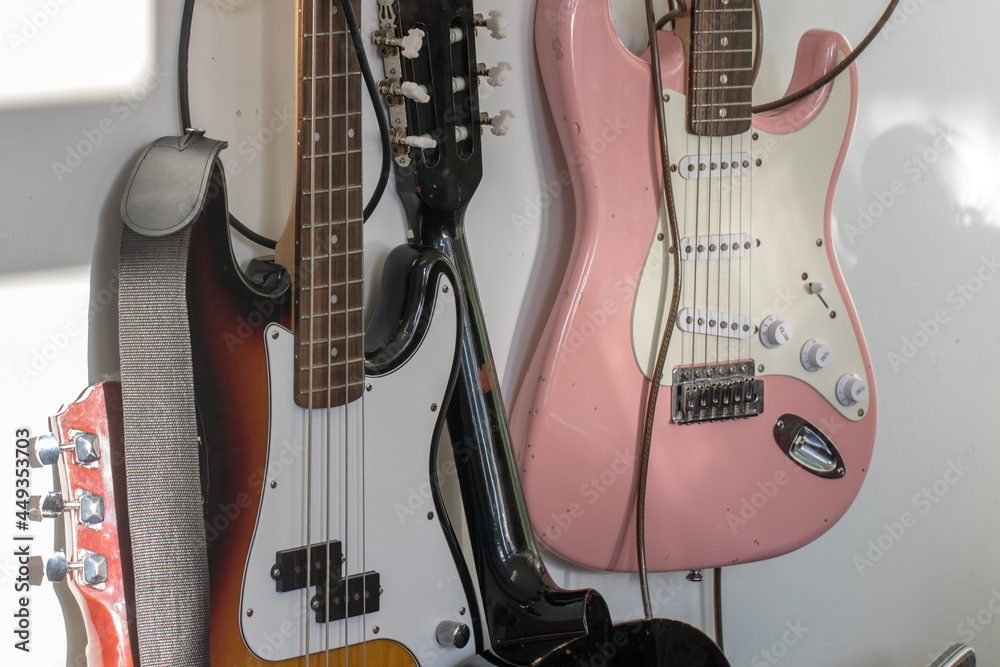 Naklejka premium Old battered guitars hanging on a music room wall.