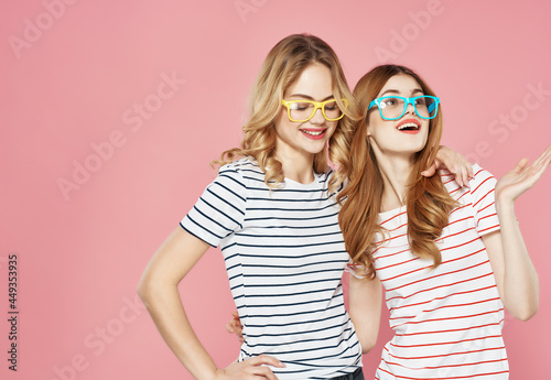 two cheerful girls are standing next to each other hugs fashion summer pink background