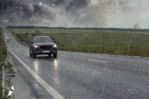 Фотография View of country road with car on rainy day