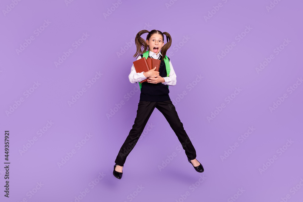 Photo of impressed glad schoolgirl jump hold book wear backpack glasses uniform isolated purple color background