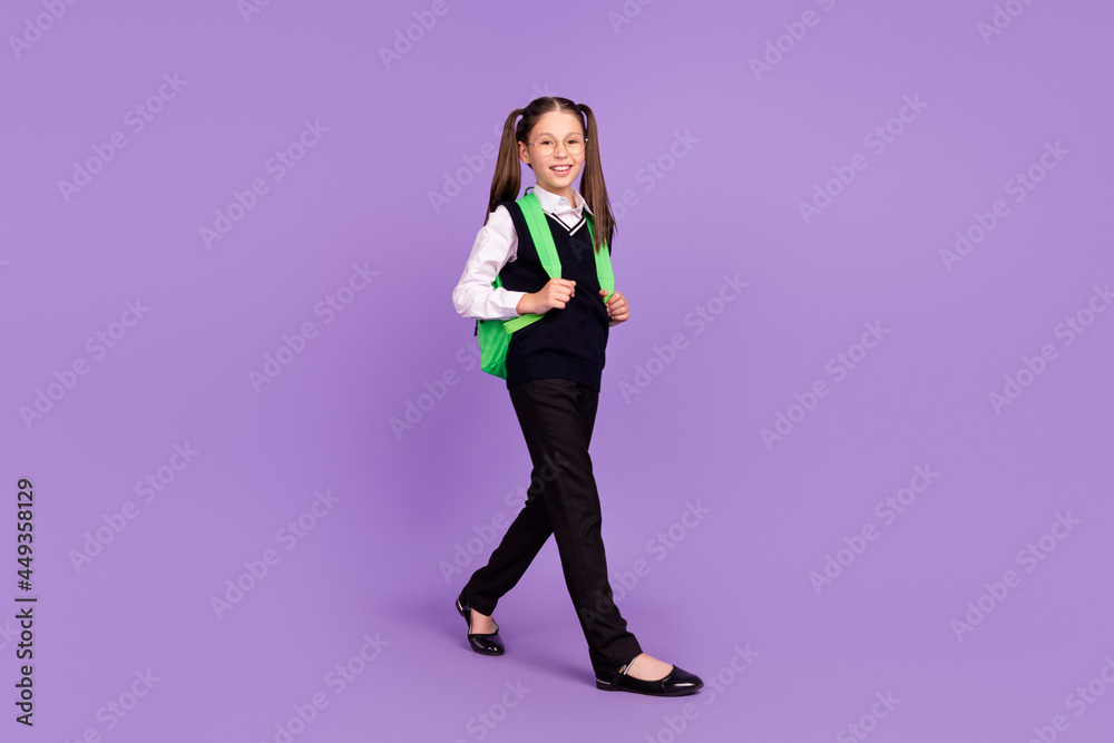 Photo of little pupil girl carry bag enjoy walk wear glasses uniform isolated violet color background Photo of little pupil girl carry bag enjoy walk wear glasses uniform isolated violet color background