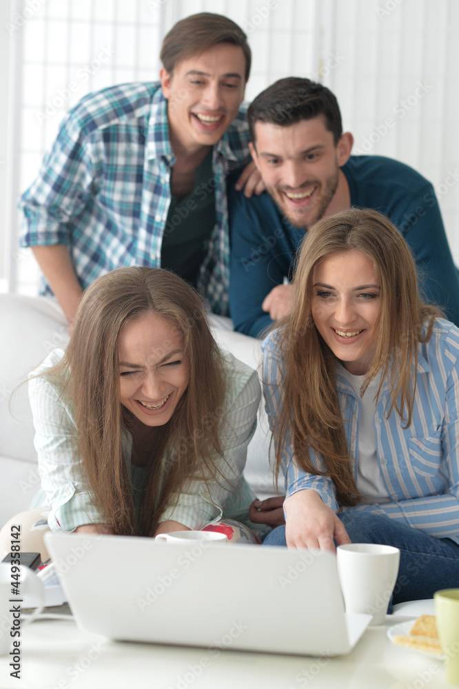 Group of young people sitting at the table with laptop and smiling Group of young people sitting at the table with laptop and smiling