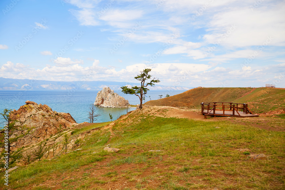 Shamanka Rock and an old larch tree on the island of Olkhon. Beautiful summer landscape of Lake Baikal.