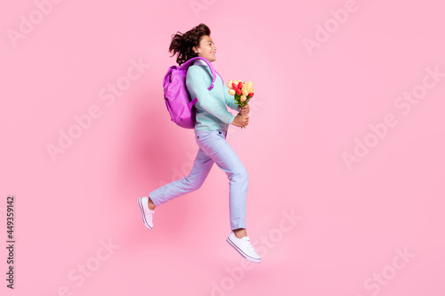 Profile photo of glad nice boy jump hold tulips run wear bag teal shirt pants sneakers isolated pink color background