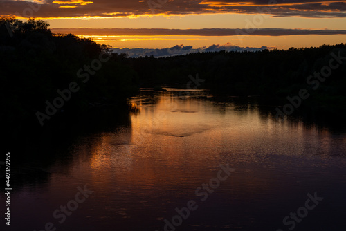 Fototapeta Naklejka Na Ścianę i Meble -  Evening sky with dramatic clouds over the river. A dramatic sunset over the river with a reflection in the water.