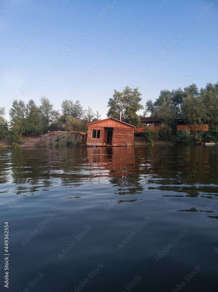 Obraz premium Old, abandoned, collapsed wooden house on the water on the river.