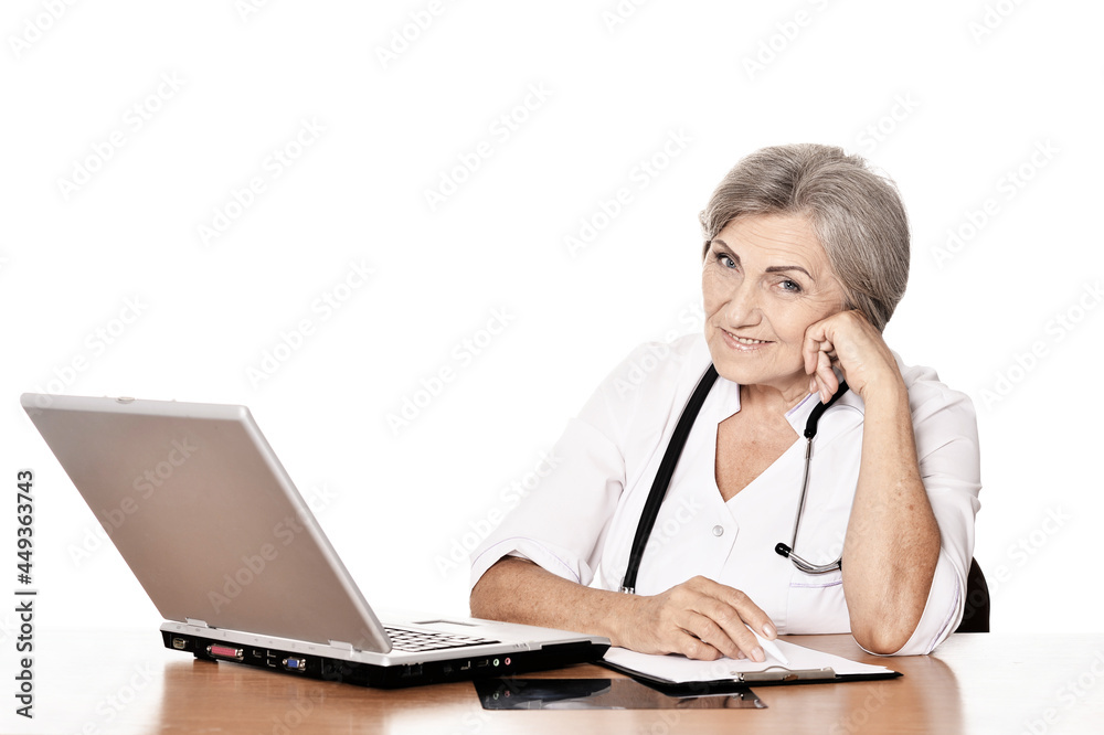 elderly woman doctor sitting at table with computer elderly woman doctor sitting at table with computer