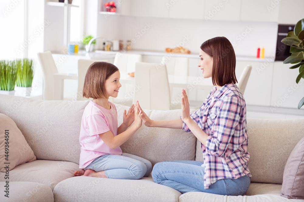 Portrait of two attractive cheerful girls sitting on divan having fun laying game at home flat indoors Portrait of two attractive cheerful girls sitting on divan having fun laying game at home flat indoors