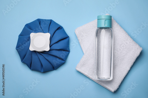 Bottle of water, cold compress and towel on light blue background, flat lay. Heat stroke treatment photo