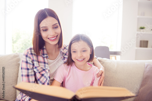 Photo of cheerful happy positive siblings sisters read book smile good mood bond indoors inside house home