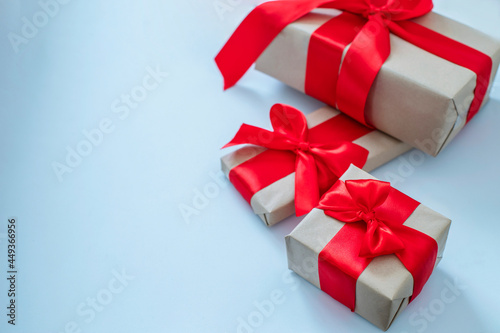 Fototapeta Naklejka Na Ścianę i Meble -  Christmas present wrapped with bright red bows on light blue background